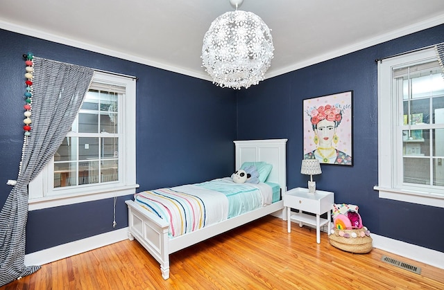 bedroom with a chandelier, visible vents, crown molding, and wood finished floors