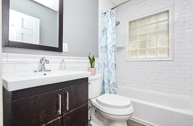 bathroom featuring shower / bath combo, toilet, a wainscoted wall, vanity, and tile walls