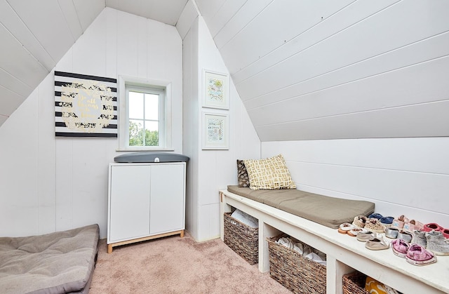 sitting room featuring lofted ceiling, light colored carpet, and wood walls