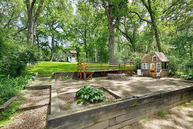 view of yard with an outbuilding, an outdoor fire pit, a playground, and fence