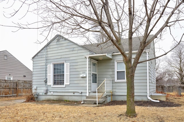 bungalow-style house with roof with shingles and fence