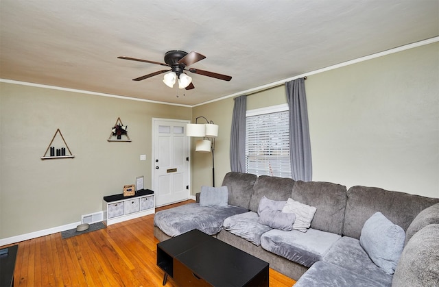 living area with visible vents, baseboards, a ceiling fan, wood finished floors, and crown molding