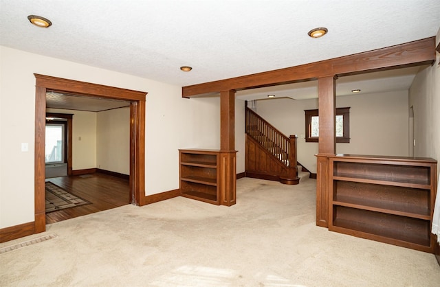 below grade area featuring carpet floors, baseboards, stairway, and a textured ceiling