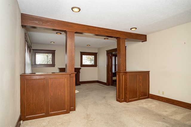 hallway featuring baseboards, light colored carpet, and ornate columns