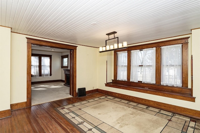 unfurnished room featuring ornamental molding, dark wood-type flooring, a chandelier, and visible vents