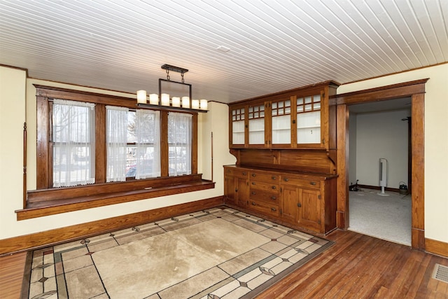 unfurnished room with an inviting chandelier, baseboards, visible vents, and dark wood-style flooring