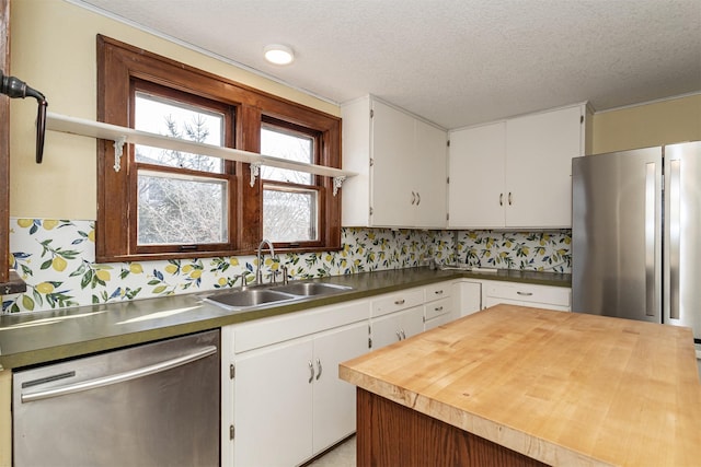 kitchen with appliances with stainless steel finishes, white cabinetry, a sink, and a textured ceiling