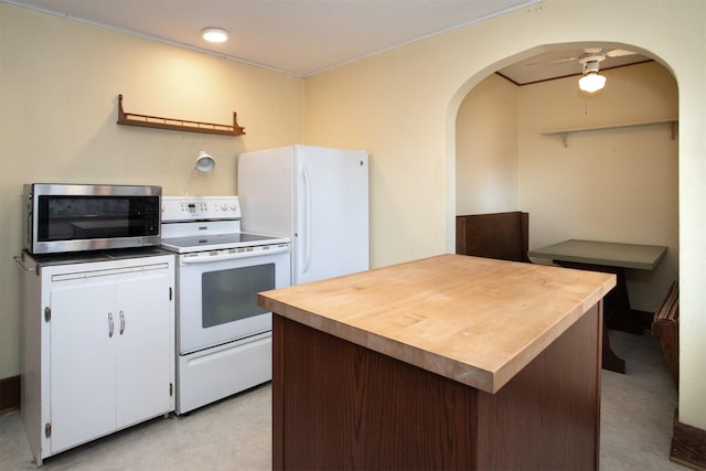 kitchen featuring butcher block countertops, arched walkways, white appliances, and white cabinetry