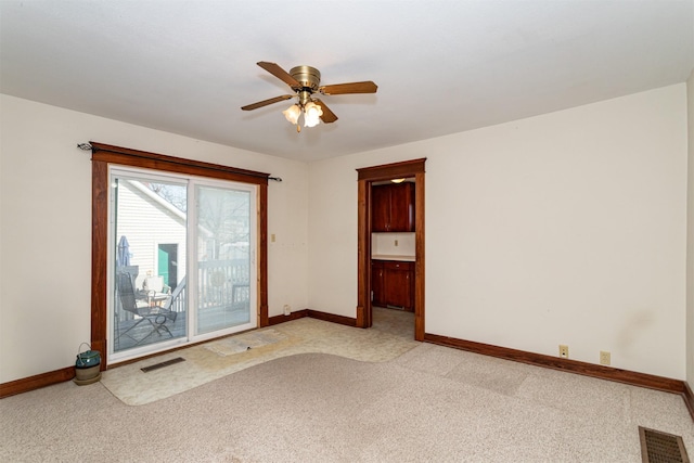 spare room featuring light carpet, visible vents, and baseboards