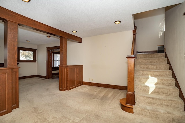 spare room featuring decorative columns, stairway, light carpet, a textured ceiling, and baseboards