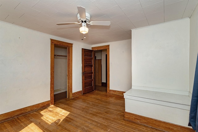 unfurnished bedroom with a closet, ceiling fan, baseboards, and wood finished floors