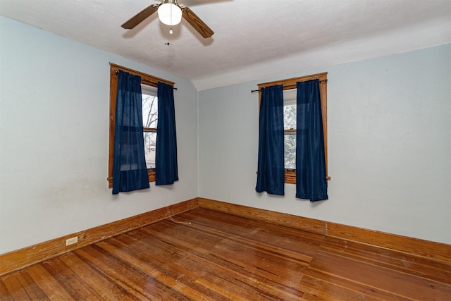 unfurnished room featuring lofted ceiling, a ceiling fan, hardwood / wood-style flooring, and baseboards