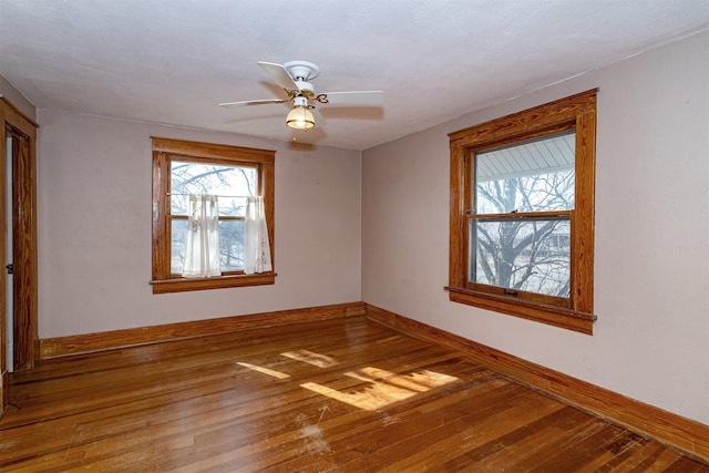 spare room featuring a ceiling fan, wood-type flooring, and baseboards