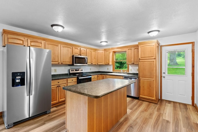 kitchen with appliances with stainless steel finishes, plenty of natural light, a sink, and light wood-style floors