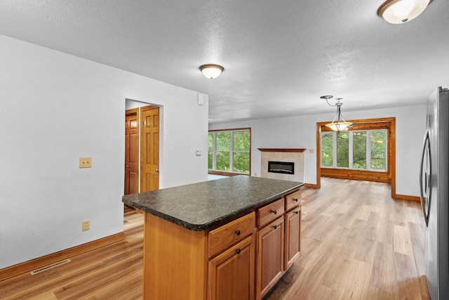 kitchen featuring visible vents, light wood-type flooring, dark countertops, and freestanding refrigerator