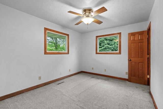 empty room featuring a ceiling fan, carpet, baseboards, and a textured ceiling