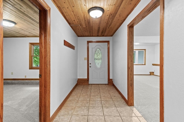 interior space with light carpet, wooden ceiling, light tile patterned floors, and baseboards