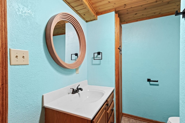 bathroom with toilet, a textured wall, wooden ceiling, and vanity