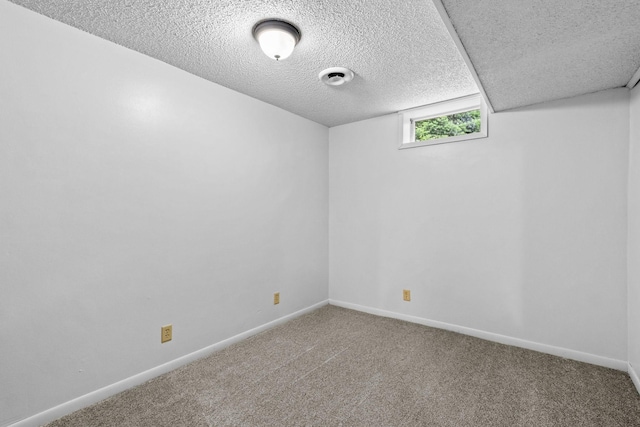 carpeted spare room with baseboards and a textured ceiling