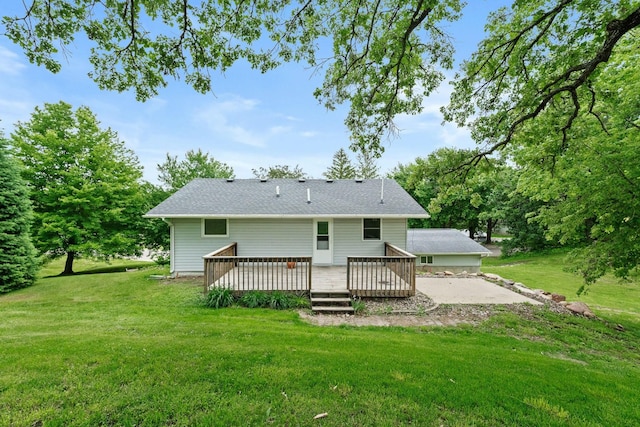 back of house with a shingled roof, a lawn, and a wooden deck