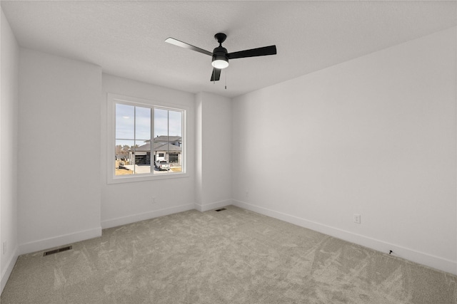 spare room featuring visible vents, a textured ceiling, carpet, baseboards, and ceiling fan