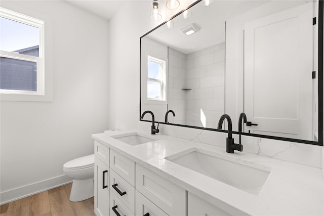 full bathroom featuring double vanity, toilet, wood finished floors, and a sink