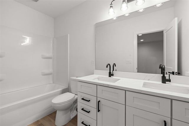 full bathroom with double vanity, toilet, wood finished floors, and a sink