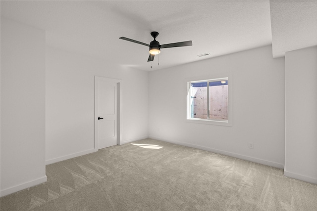 carpeted empty room with visible vents, baseboards, and a ceiling fan