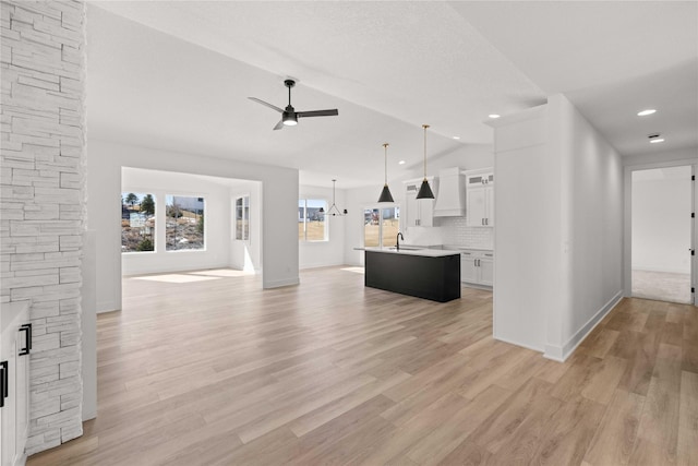 unfurnished living room with baseboards, ceiling fan, vaulted ceiling, light wood-style flooring, and a fireplace