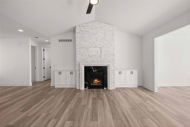 unfurnished living room with light wood-style flooring, a fireplace, baseboards, and vaulted ceiling