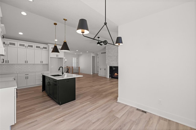 kitchen with visible vents, a sink, tasteful backsplash, a fireplace, and light countertops