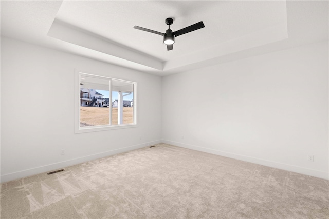 empty room featuring baseboards, visible vents, a raised ceiling, and carpet floors