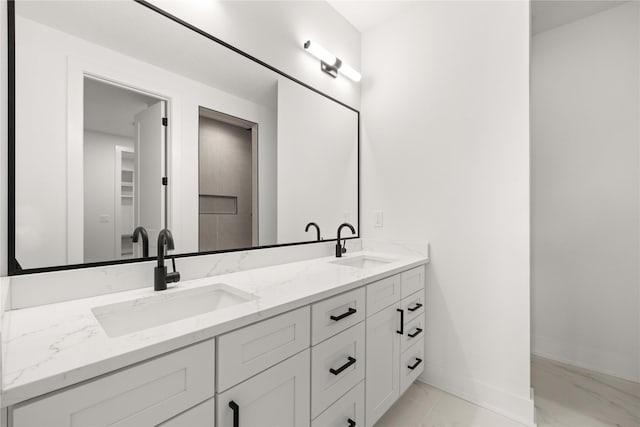 bathroom with a sink, baseboards, marble finish floor, and double vanity