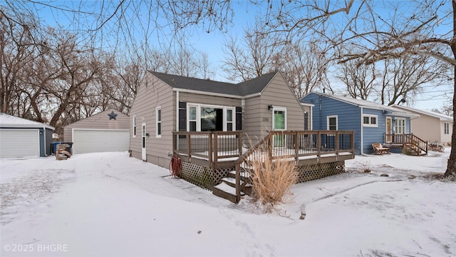 view of front of house with a wooden deck, a detached garage, and an outbuilding