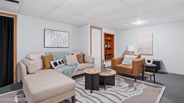 living room featuring concrete flooring and a paneled ceiling