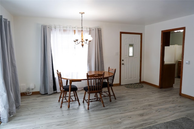 dining room featuring baseboards, light wood-style flooring, and a notable chandelier