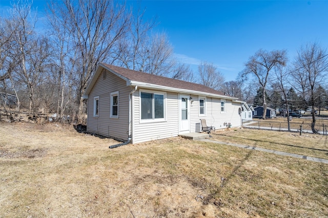 exterior space with roof with shingles, fence, and a front lawn