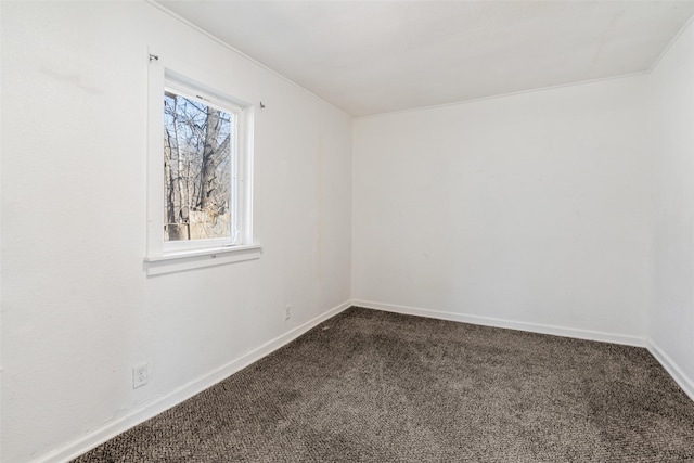 spare room featuring baseboards and dark carpet