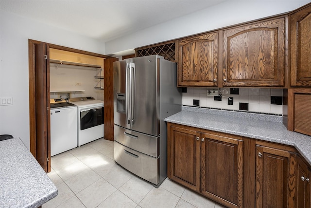 kitchen featuring light tile patterned floors, light countertops, stainless steel refrigerator with ice dispenser, backsplash, and washing machine and clothes dryer