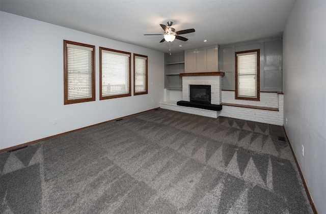 unfurnished living room with dark colored carpet, a fireplace, plenty of natural light, and baseboards