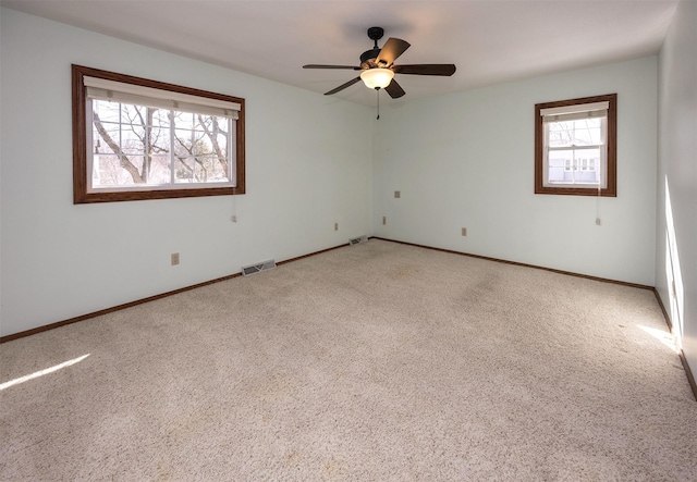 spare room with light carpet, baseboards, visible vents, and a ceiling fan