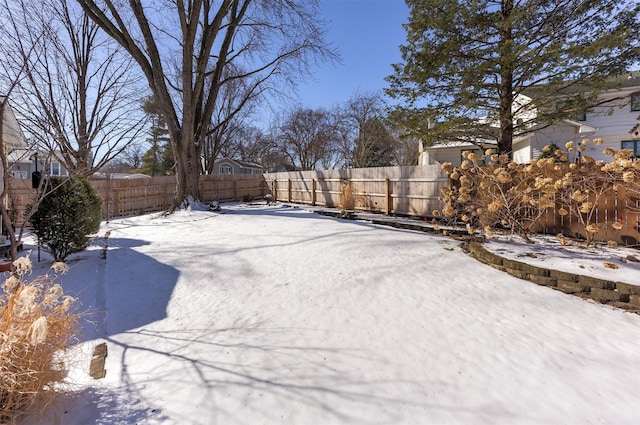 yard layered in snow with a fenced backyard