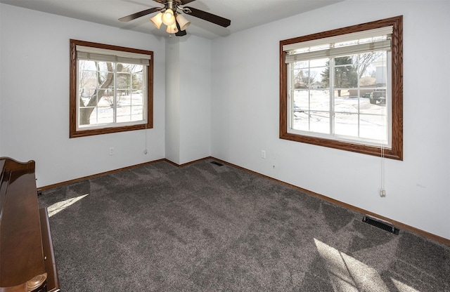 unfurnished room with a ceiling fan, visible vents, dark carpet, and baseboards