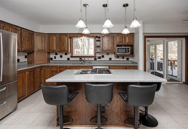 kitchen featuring a breakfast bar area, stainless steel appliances, tasteful backsplash, a kitchen island, and a sink