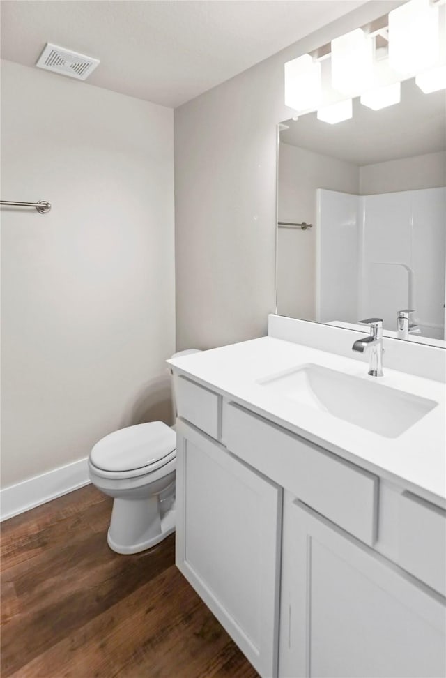 bathroom featuring toilet, wood finished floors, vanity, visible vents, and baseboards