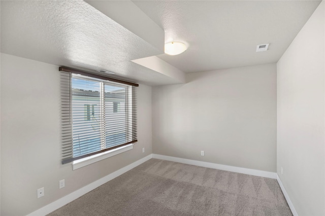 unfurnished room featuring baseboards, a textured ceiling, visible vents, and light colored carpet