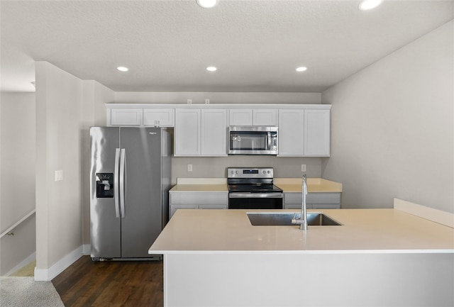 kitchen featuring recessed lighting, stainless steel appliances, a sink, white cabinets, and dark wood finished floors