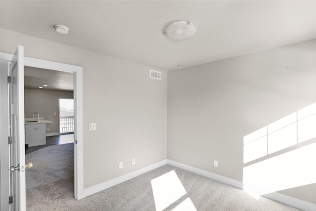 unfurnished room featuring baseboards, visible vents, and carpet flooring