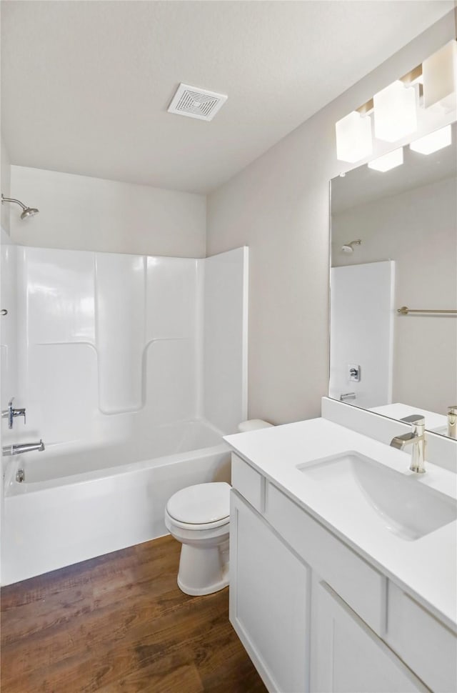 full bath with visible vents, toilet, wood finished floors, tub / shower combination, and vanity