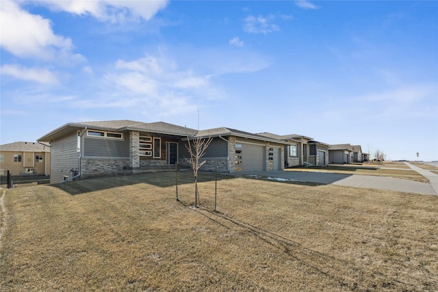 prairie-style house with an attached garage, stone siding, driveway, and a front yard